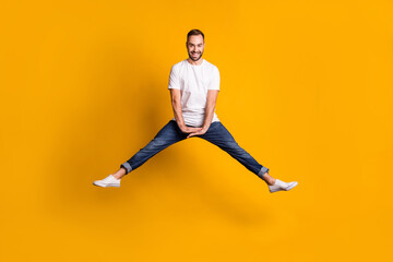 Fototapeta na wymiar Full length body size photo of jumping man cheerful playful laughing isolated bright yellow color background
