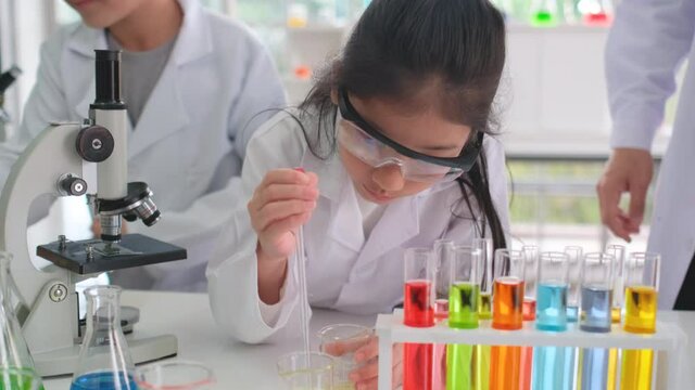 Young scientist girl lean to use dropper to mix chemical or do experiment with classmate and teacher in laboratory or classroom. Science equipment and tools for study and support education concept.