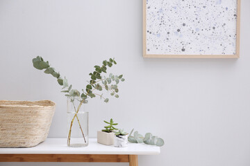 Vase with fresh eucalyptus branches on table in room. Interior design