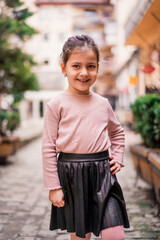 Portrait of small beautiful happy girl child posing outdoors in city