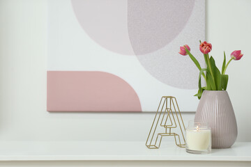 Vase with beautiful tulips, burning candle and decorative letter on table indoors, space for text. Interior elements