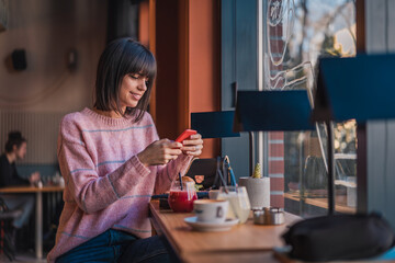 Beautiful happy female in cafe using mobile phone