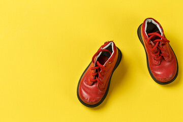 Children's shoes in red on a yellow background.