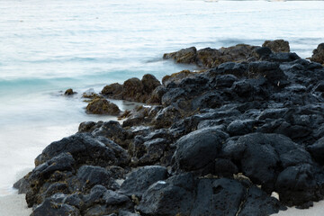 Fototapeta na wymiar Dark volcanic rocks on a beach by the sea in Mauritius