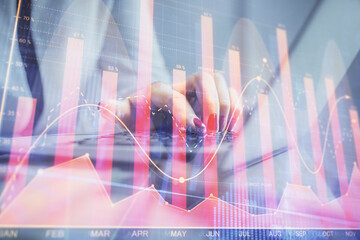 Double exposure of businesswoman hands typing on computer and financial graph hologram drawing. Stock market analysis concept.