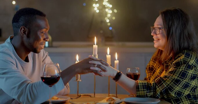 Happy couple celebrating valentine's day. They drink wine in glasses and eat pizza by candlelight.