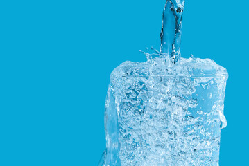 Pouring clean drinking water from blue plastic bottle into glass on blue background