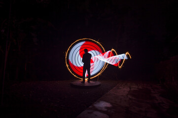 one person standing against beautiful red and white circle light painting as the backdrop