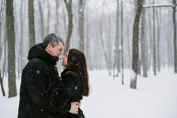 Fototapeta premium A man and a woman on the background of a snow-covered forest in a snowfall