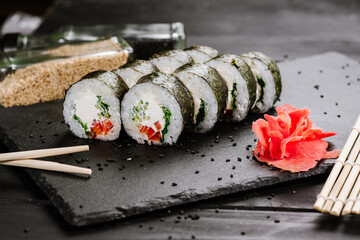 Appetizing sushi rolls with seafood on black background. Japanese food