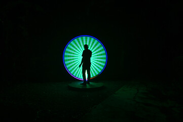 one person standing against beautiful blue and green circle light painting as the backdrop