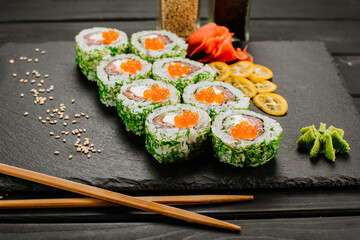 Tasty sushi rolls with seafood and caviar on black background