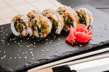 Delicious fresh sushi rolls with seafood and cream cheese on black background