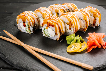 Delicious fresh sushi rolls with seafood and cream cheese on black background