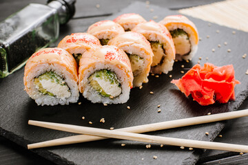 Tasty fresh sushi rolls with salmon on black background
