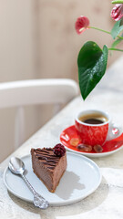 Classic chocolate cheesecake and a cup of coffee on light gray concrete background. Homemade baking.