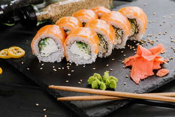 Tasty fresh sushi rolls with salmon on black background