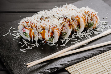 Delicious fresh sushi rolls with seafood and cream cheese on black background