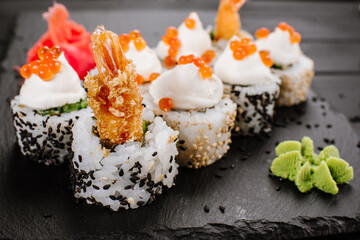 Fresh sushi rolls with srimp and red caviar on black background