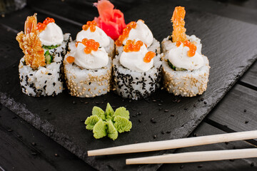 Fresh sushi rolls with srimp and red caviar on black background