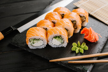 Tasty fresh sushi rolls with salmon on black background