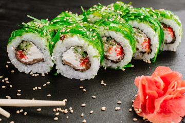Sushi rolls with seafood and Chuka salad on black background