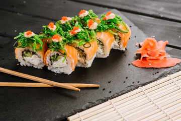 Tasty fresh sushi rolls with salmon on black background