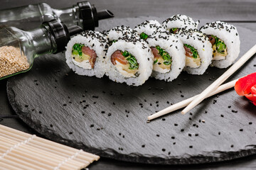 Appetizing sushi rolls with seafood on black background. Japanese food