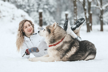 Girl playing with siberian husky in winter forest and park