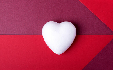 White foam plastic heart on two colored geometric background. Valentine's Day backdrop