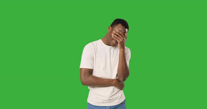 Depressed african american man crying over green background
