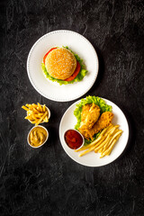 Burger with fried potatoes and chicken, top view