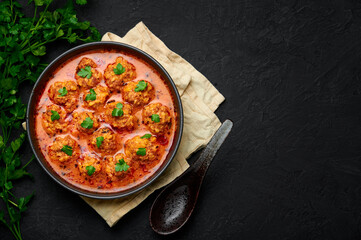Sulu Kofte in black bowl on dark slate table top. Turkish cuisine soup dish with beef meatballs and gravy. Traditional food. Top view. Copy space