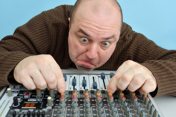 A crazy and inadequate man controls the equalizer on a mixing console in a state of narcotic...