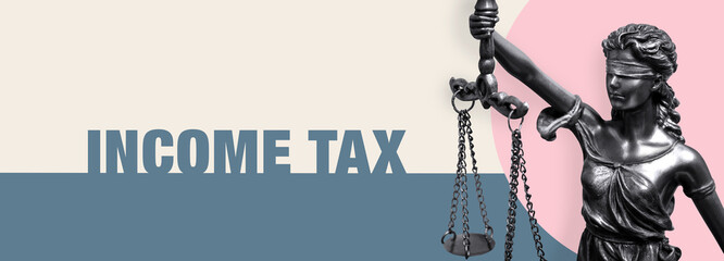 Income Tax. Close-up of a Lady Justice statue. Law and lawyer symbol. Figure stands in front of paper with text.