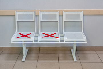 White chairs with the red crosses during COVID-19 pandemic. Coronavirus, social distancing, new normal concept