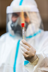 Medical worker in PPE holding COVID-19 test
