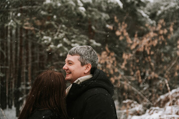 Adult man and woman on the background of a winter snow-covered pine forest