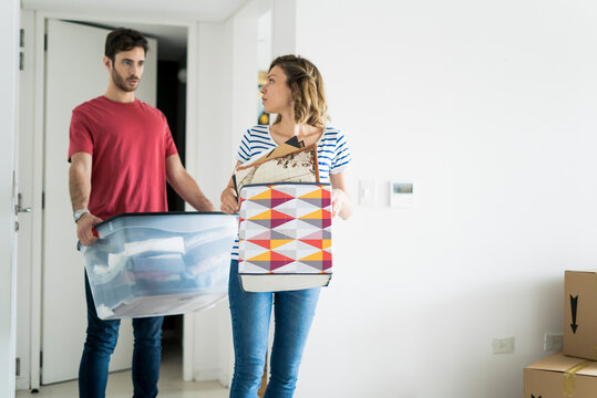 Young couple carrying boxes in their new home