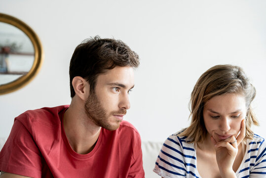 Thoughtful young couple sitting in house