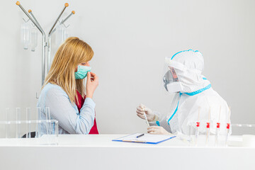 Medical worker in PPE performing nasal swab COVID-19 test in hospital lab.
