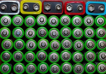 Used alkaline batteries AA size format of different brands lying in a rows. top view background texture of electric batteries and accumulators AA. AA packed close to each other. Used AA batteries

