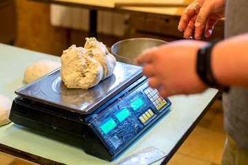 The baker weighs the dough on electronic scales.
