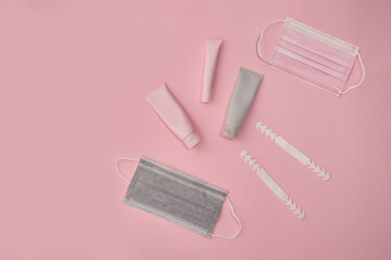 Pink and grey cosmetic tubes and masks on pink paper background. . High quality photo