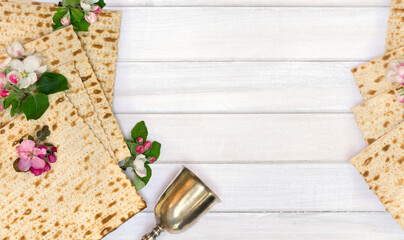 Matzo, silver bowl and pink flowers apple tree for passover celebration on background white wooden planks with space for text. Top view, flat lay