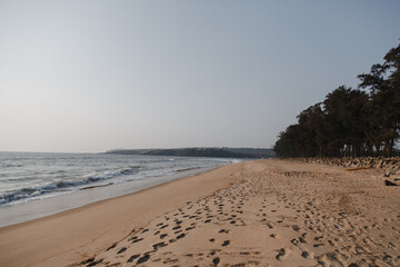 sandy beach by the sea on a sunny day with footprints in the sand