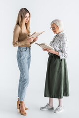 full length of young woman and granny in glasses reading books on white