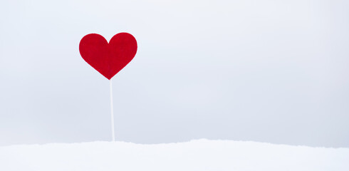 Fototapeta na wymiar Red heart on stick in the snow outdoors