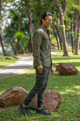  Portrait of happy asian young man in long sleeve shirt and green pant standing  in the park