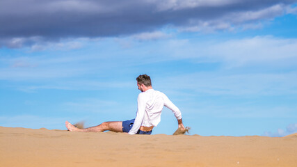 Fototapeta na wymiar Young man sitting in the desert in Gran Canaria